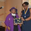 DAHF President LeSans Alexander presents Luna Isaac Mishoe's daughter Rev. Rita Mishoe Paige with his plaque